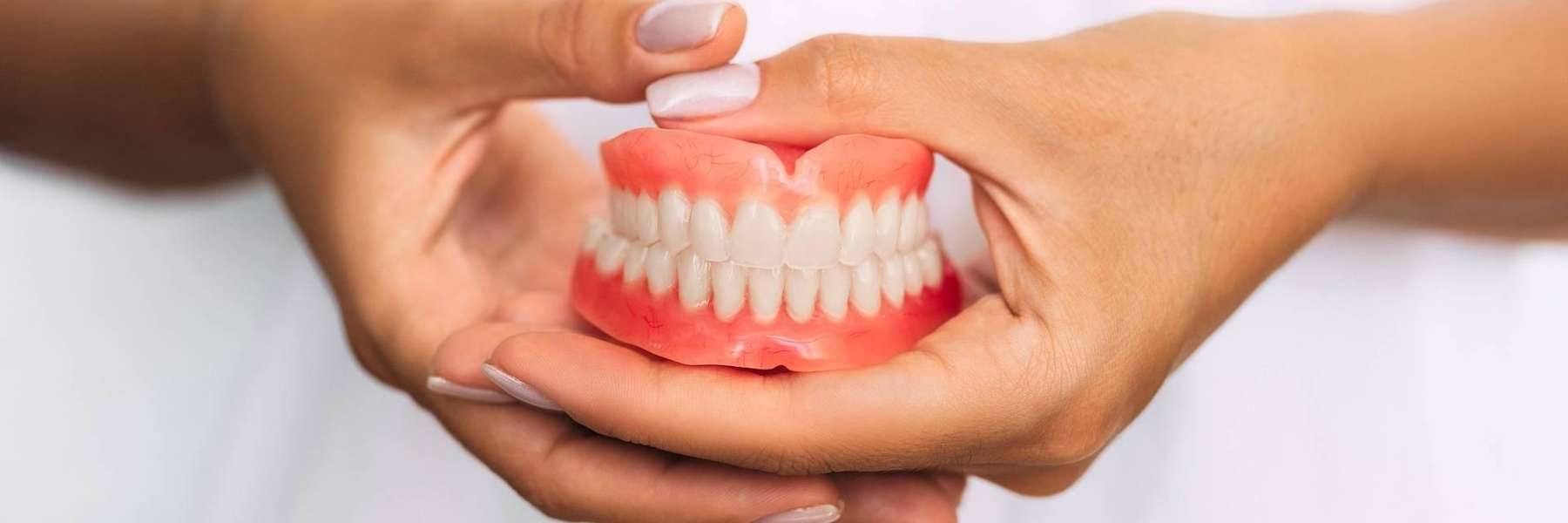 A woman holding a complete set of dentures