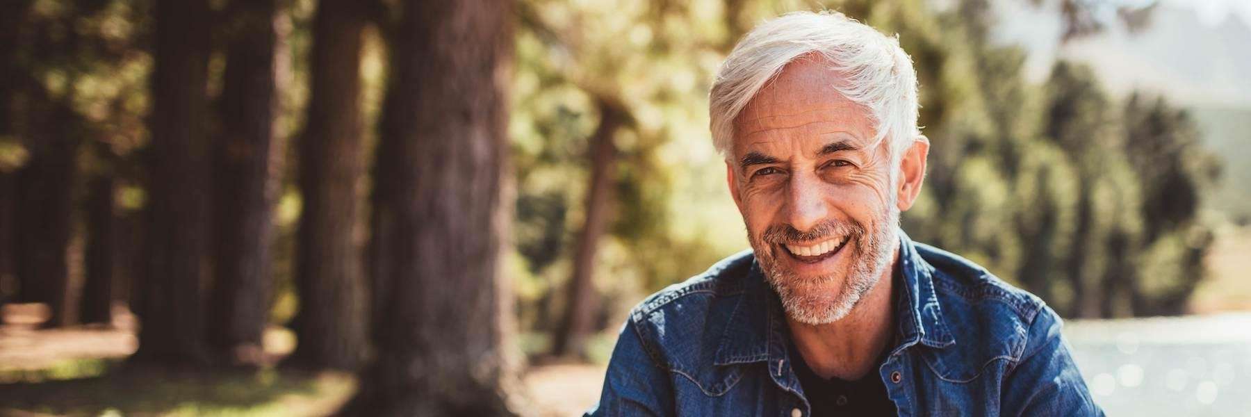 A white-haired man smiles with his upper teeth denture in Prosper TX