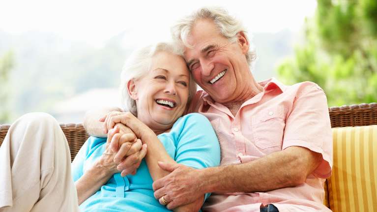 An elderly couple confidently laughs with their dentures in Prosper TX
