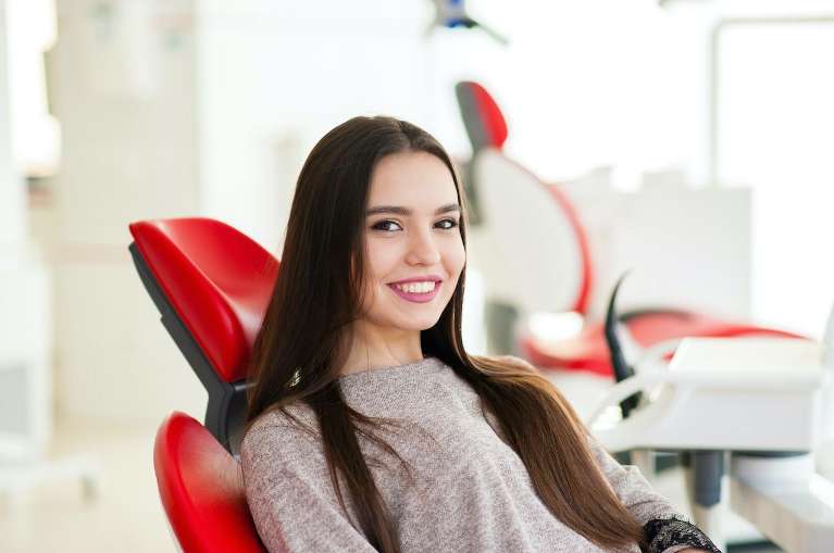 Woman in dental chair getting professional teeth whitening.