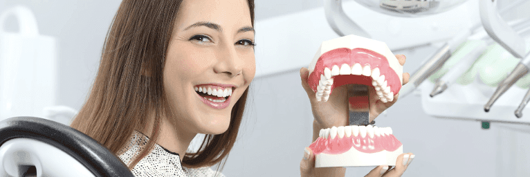 Female patient in Prosper TX holding a teeth model